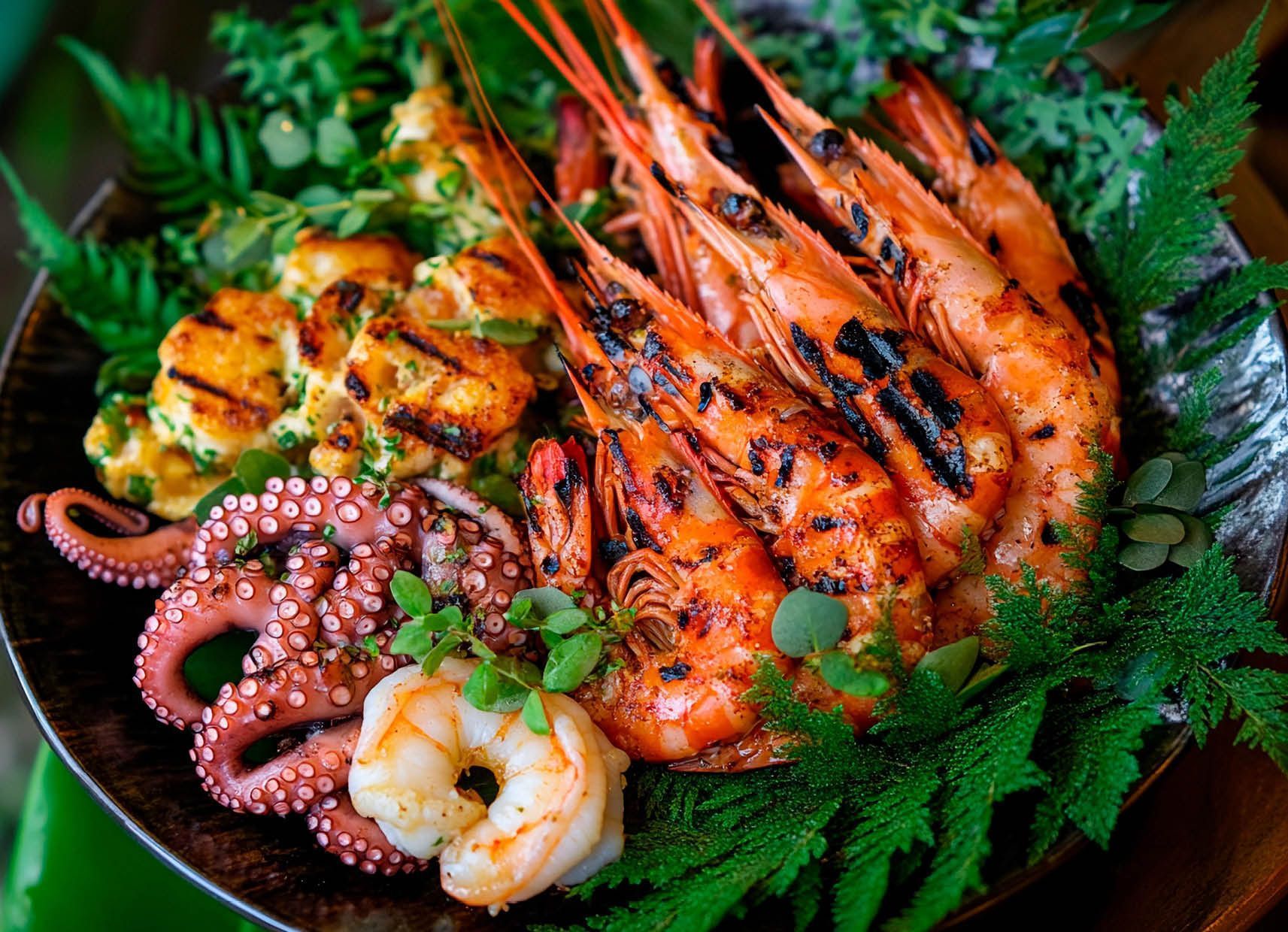 A plate of shrimp , octopus , and cauliflower on a table.
