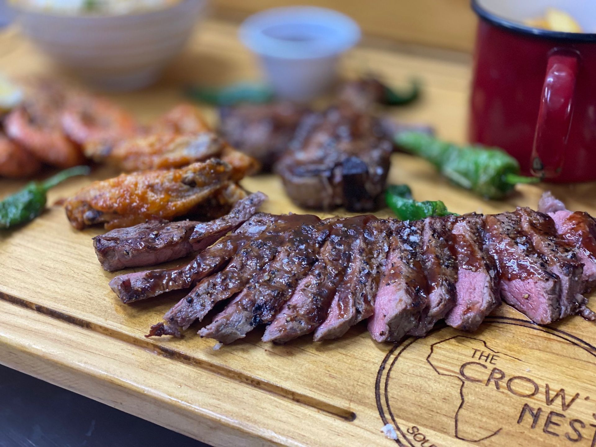 A wooden cutting board topped with sliced meat and vegetables.