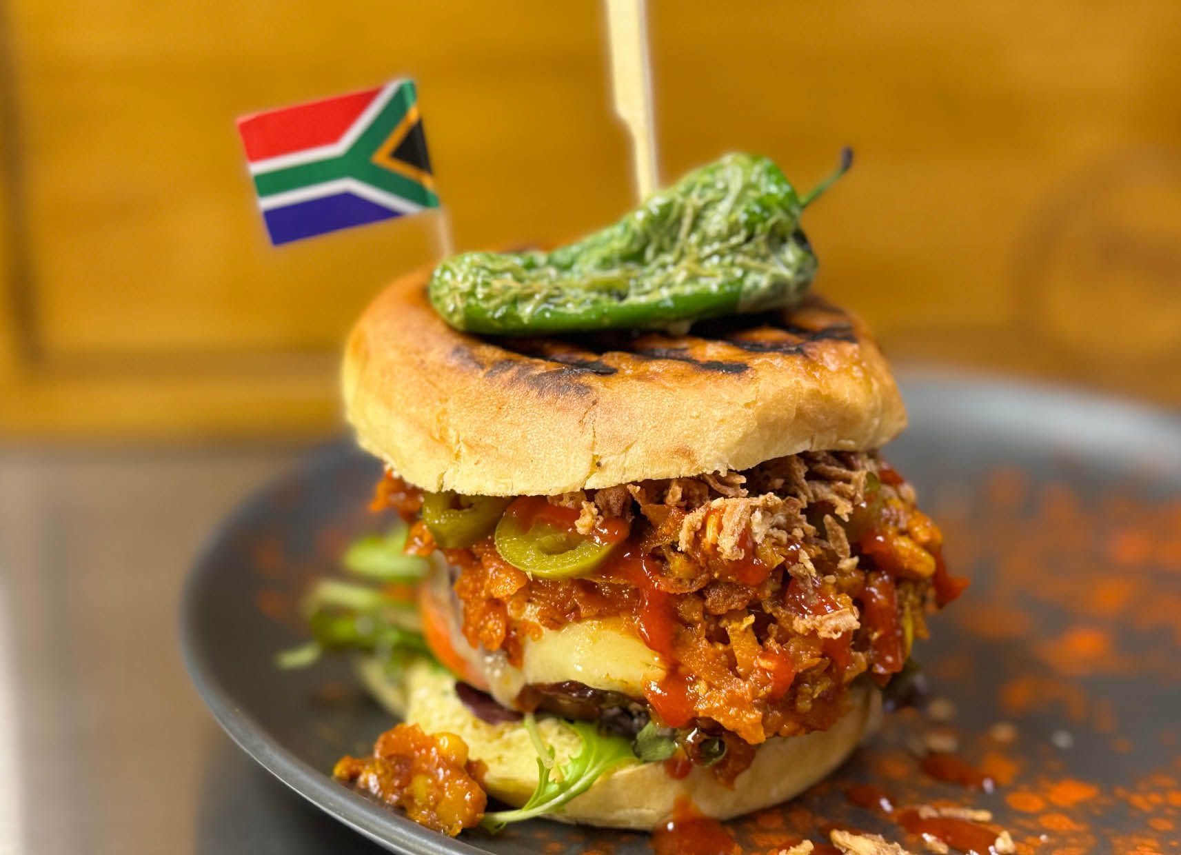 A hamburger with a flag on top of it on a plate.
