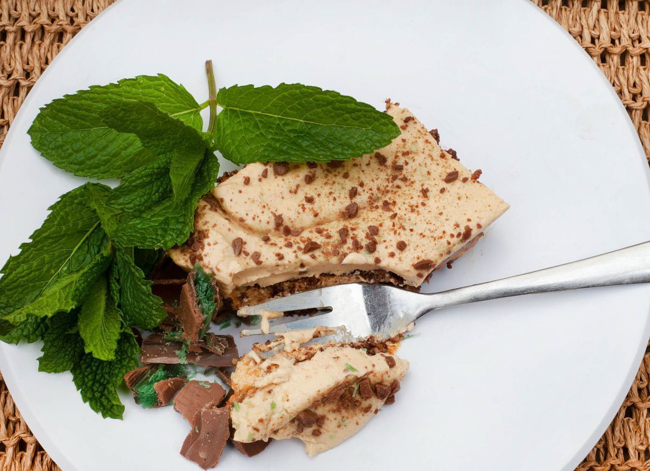 A white plate topped with a piece of cake and mint leaves