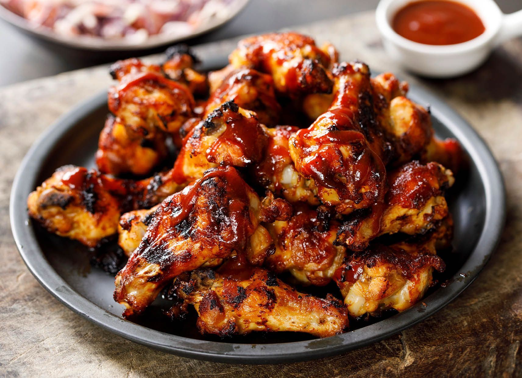 A plate of grilled chicken wings with barbecue sauce on a table.