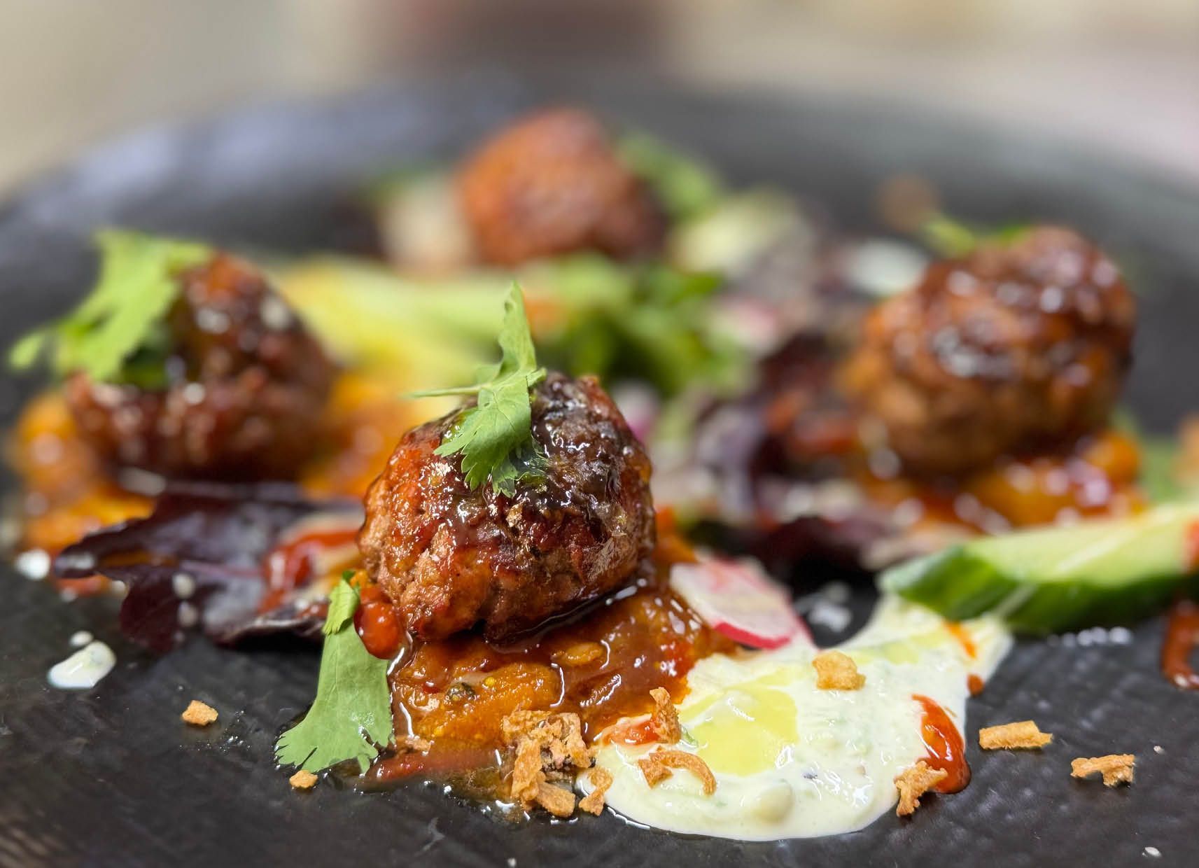 A close up of a plate of food with meatballs and vegetables on a table.