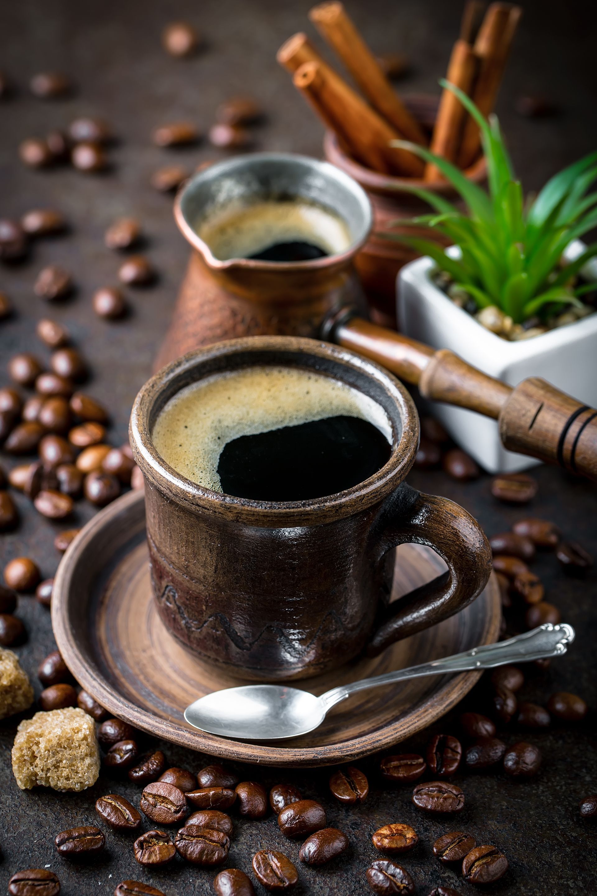 Des grains de café autour de la tasse et une cuillère.