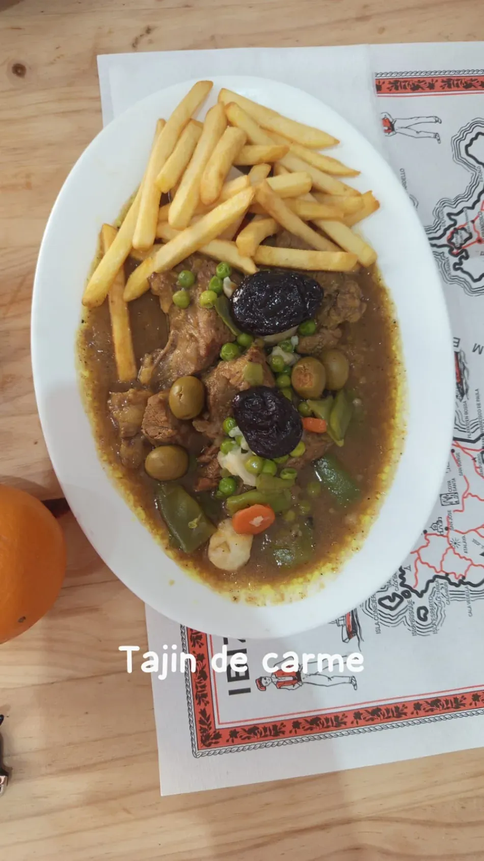 Moroccan tagine de carne with fries on a white oval plate, served on a patterned tablecloth