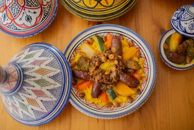 Tagines marroquíes coloridos con estofado y verduras sobre una mesa de madera.