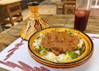طبق من اليخنة مع الأرز والسلطة والخبز المسطح على طاولة، مع إبريق شاي مزخرف ومشروب مثلج في مكان قريب.