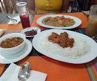 طاولة عليها أطباق أرز ودجاج في أطباق بيضاء، بالإضافة إلى وعاء من الصلصة ومشروب على مفرش طاولة برتقالي اللون