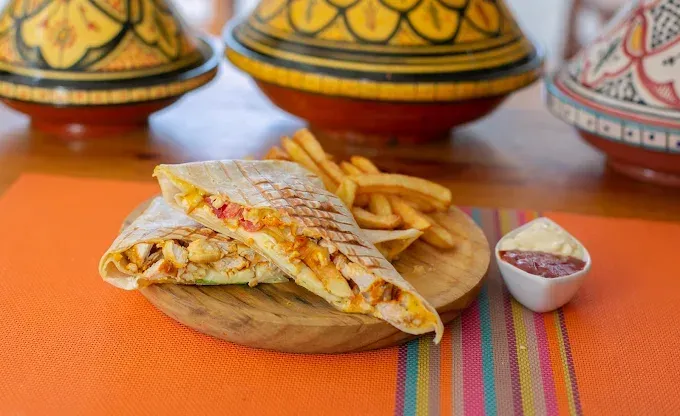 Quesadillas y papas fritas en tablas de madera con pequeños recipientes para salsa sobre un mantel a rayas.