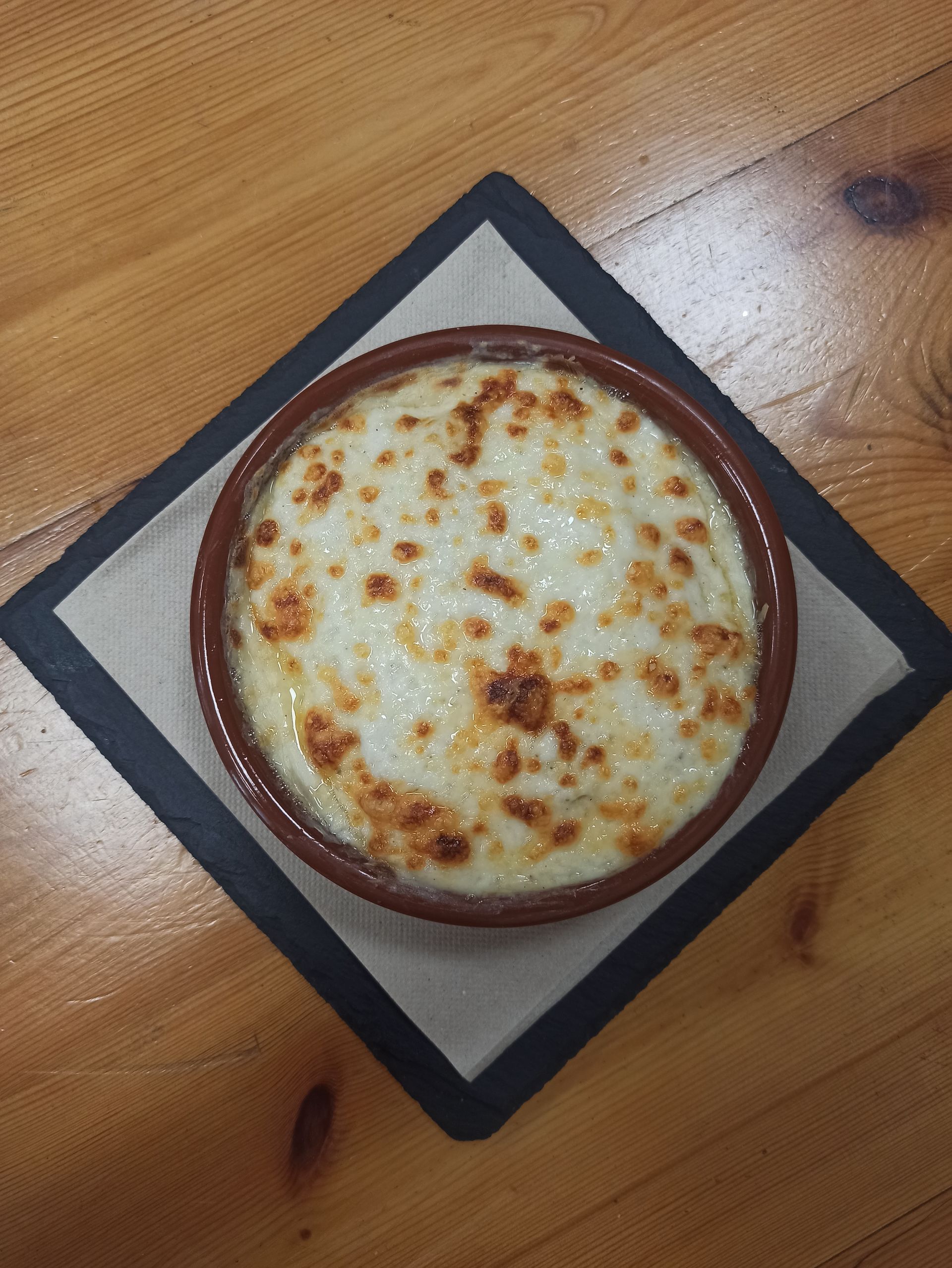 Una hamburguesa está sentada en una mesa de madera en un restaurante.