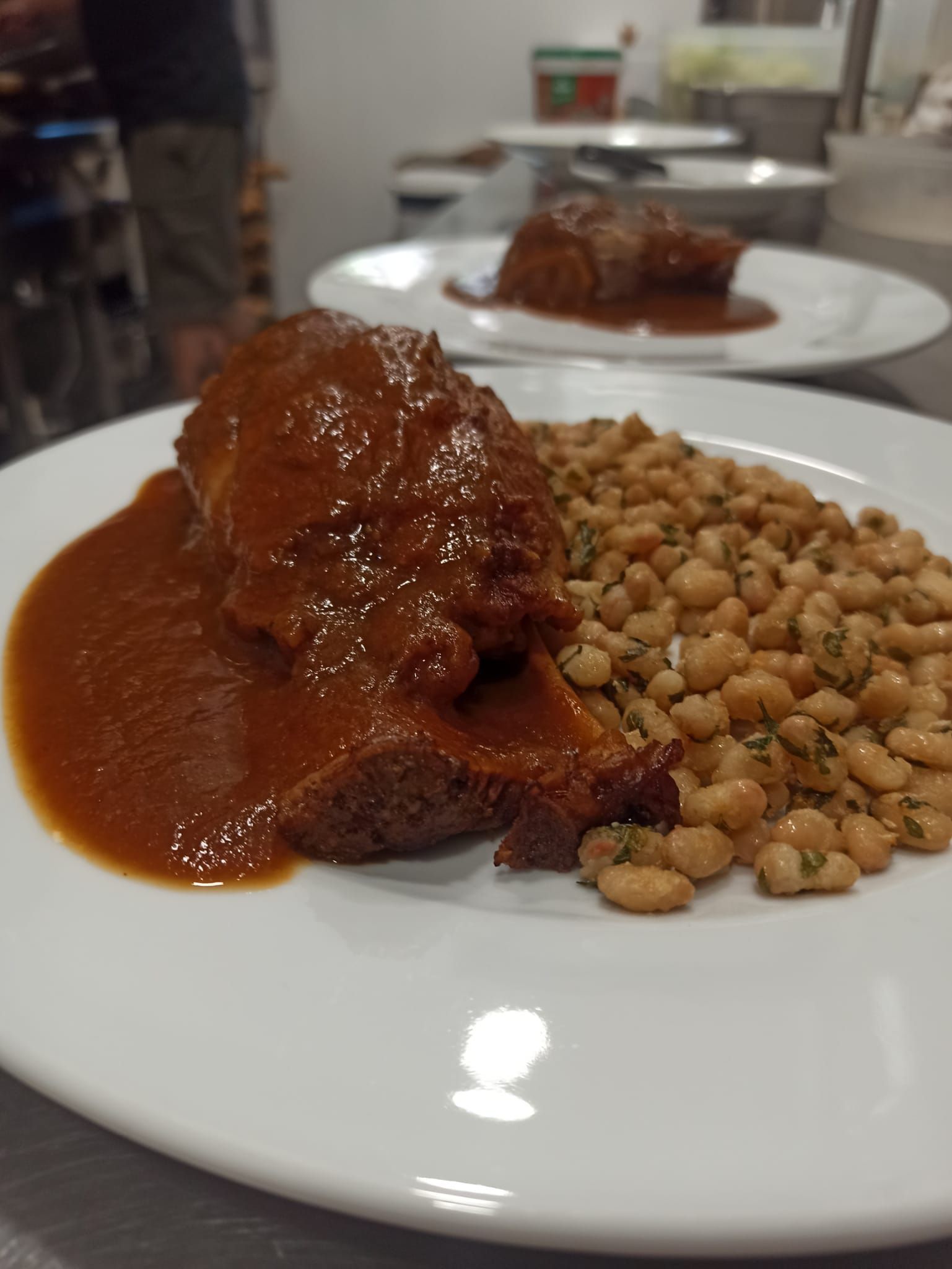 Un plato blanco cubierto con carne y frijoles sobre una mesa.