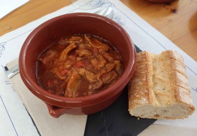 Un tazón de sopa al lado de un trozo de pan