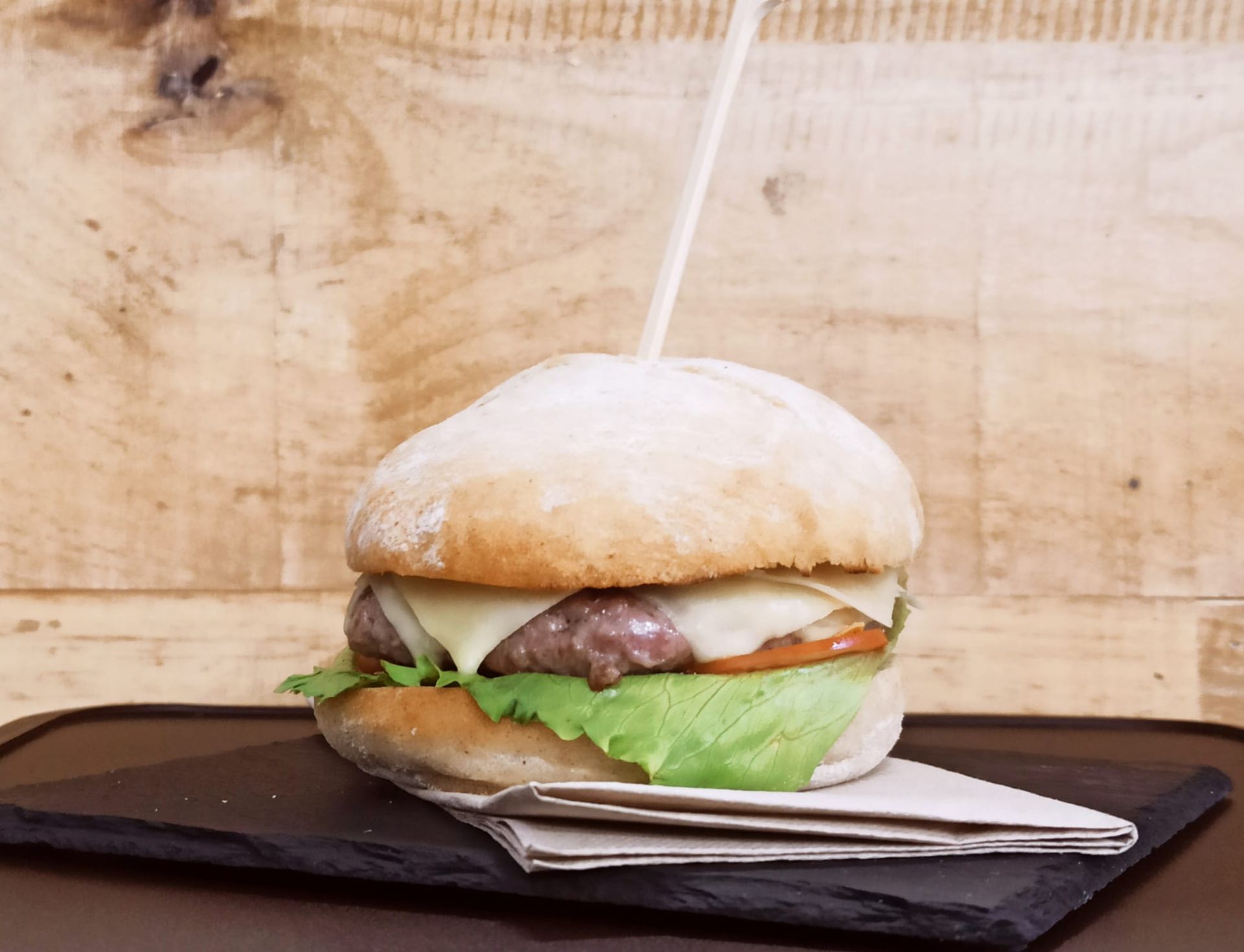 Una hamburguesa con lechuga, tomate y queso en un pan.