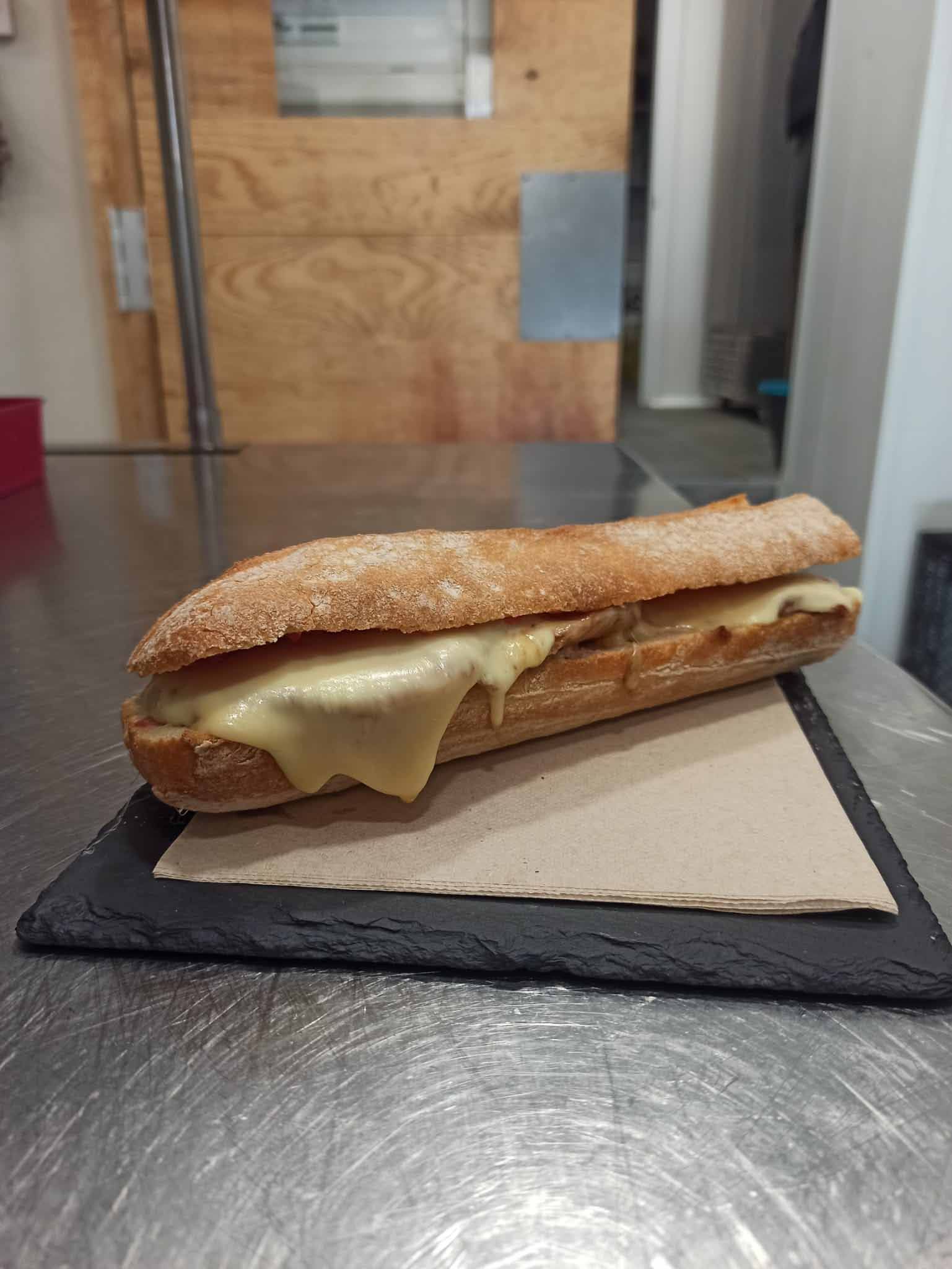 Un sándwich está sobre una tabla de cortar sobre una mesa.