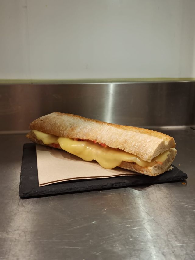 Un sándwich reposa sobre una servilleta sobre un mostrador de acero inoxidable.