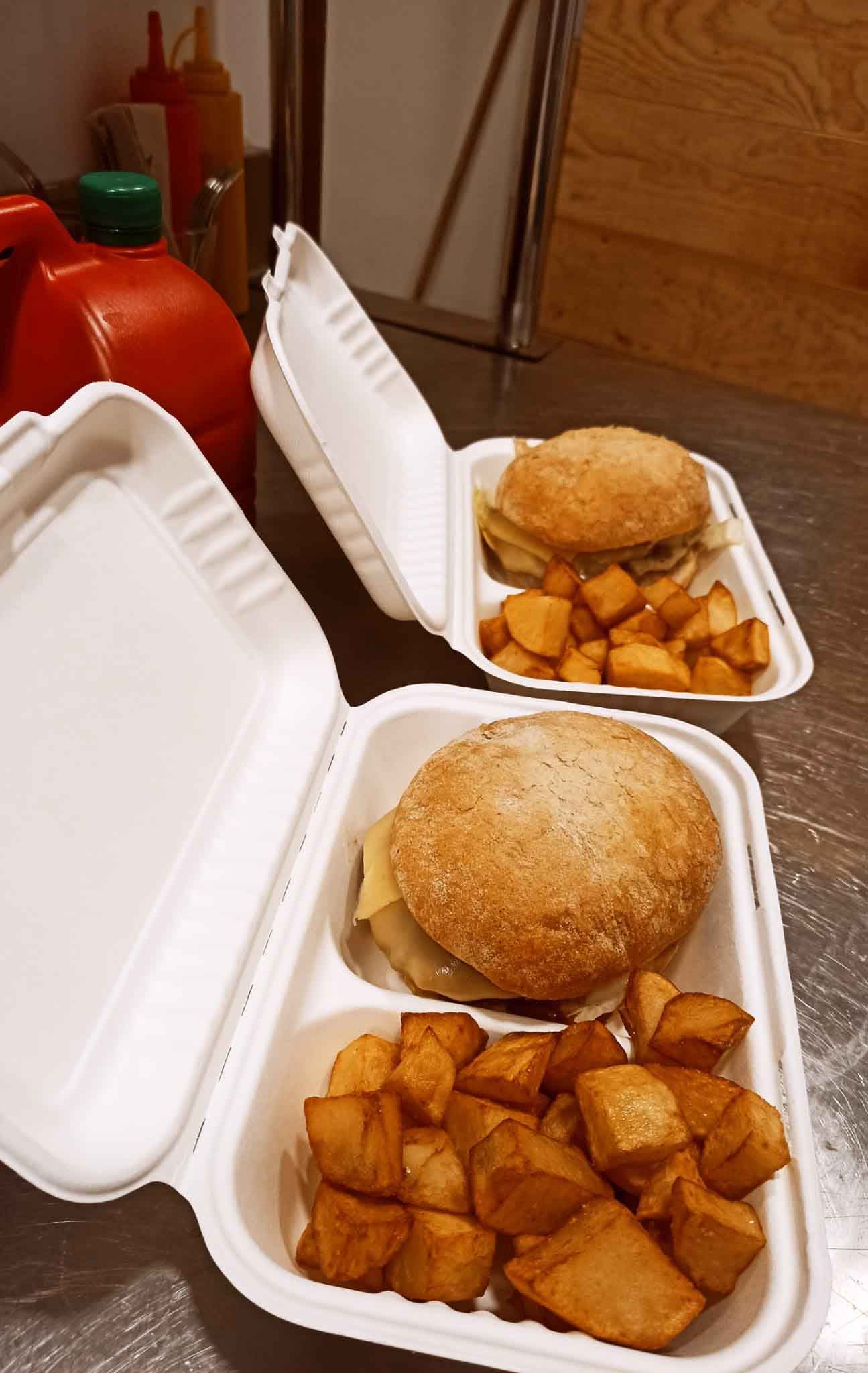 Dos recipientes de poliestireno llenos de hamburguesas y patatas