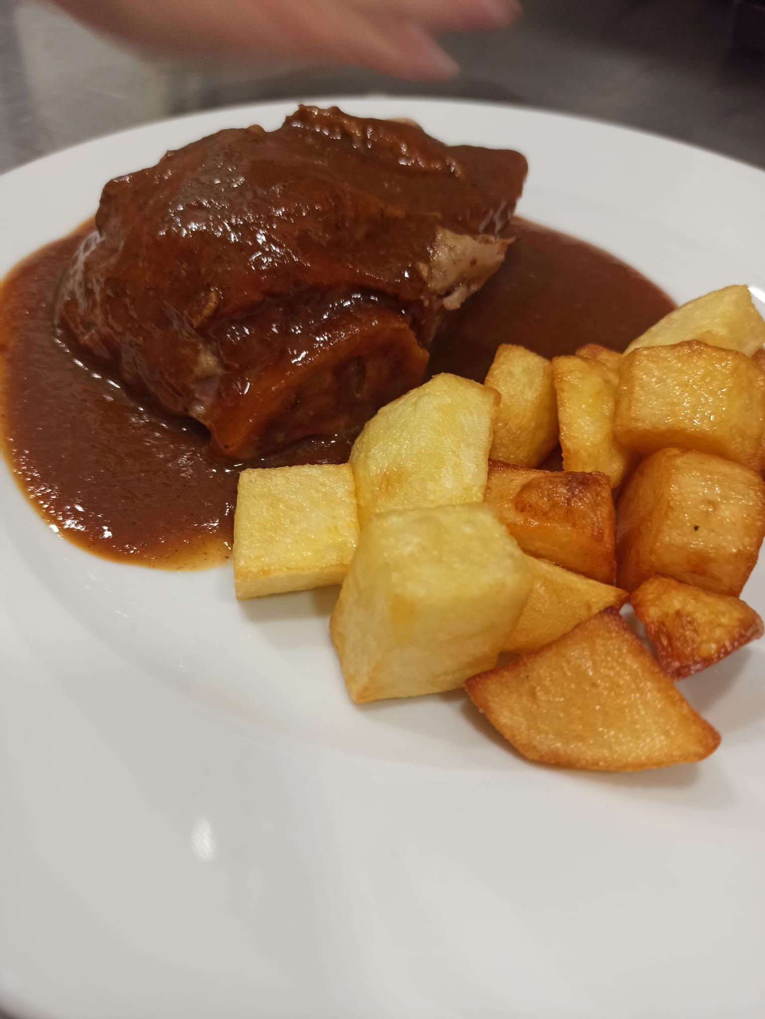 Un plato blanco cubierto con un trozo de carne y patatas fritas.