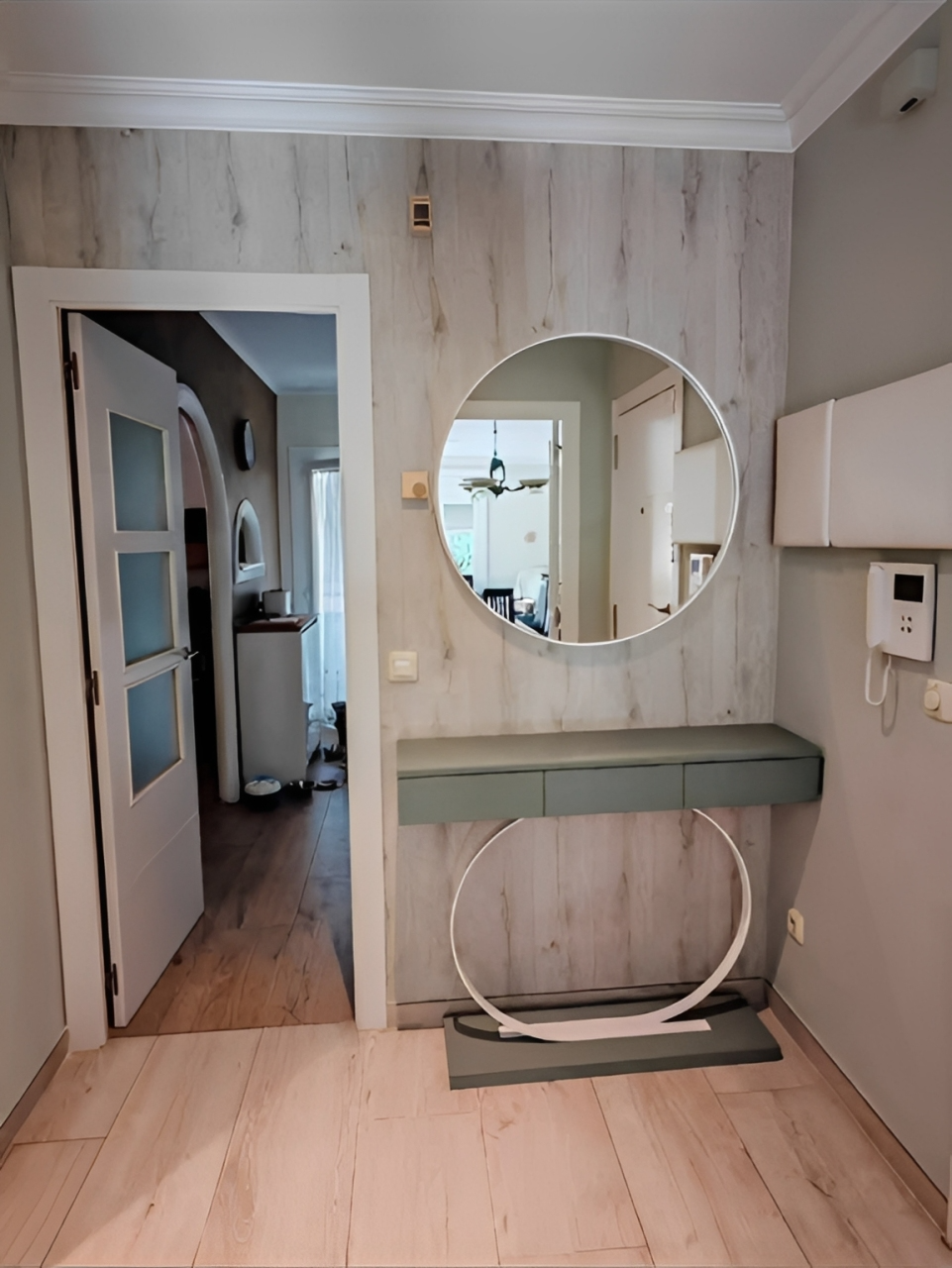 Un recibidor gris con un espejo circular