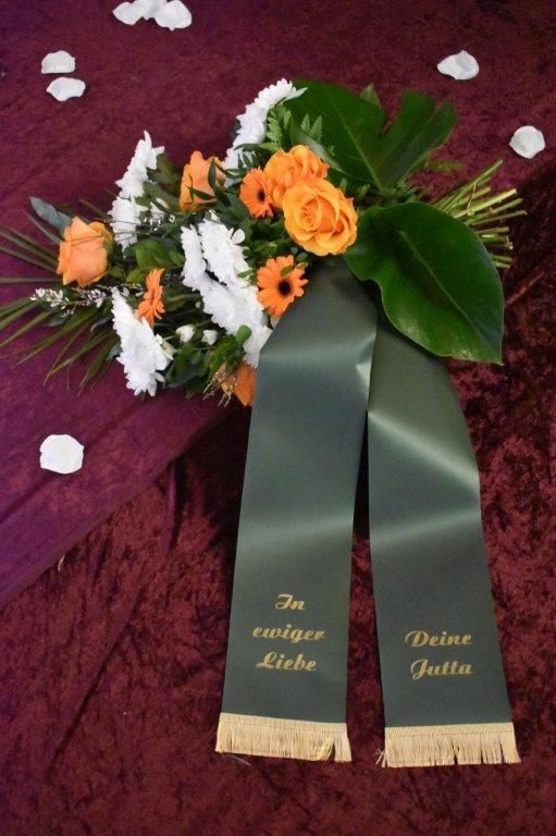 Ein Blumenstrauß mit einer grünen Schleife mit der Aufschrift „Deine Jutta“