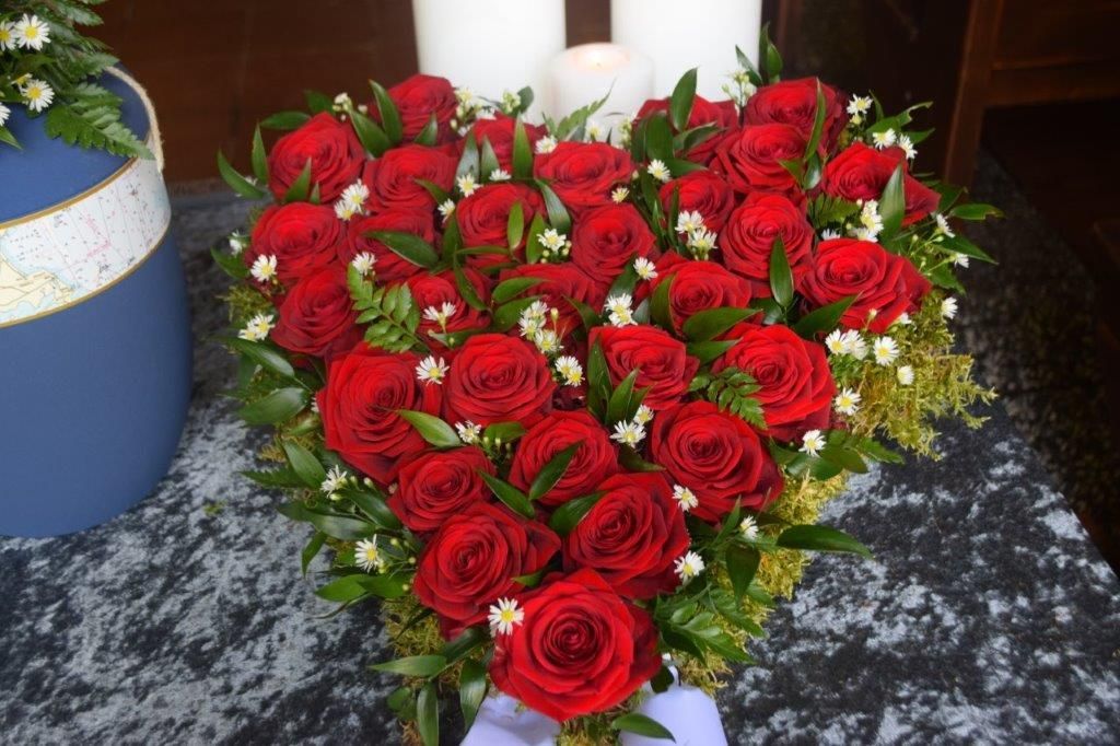 Ein herzförmiges Arrangement aus roten Rosen und weißen Blumen