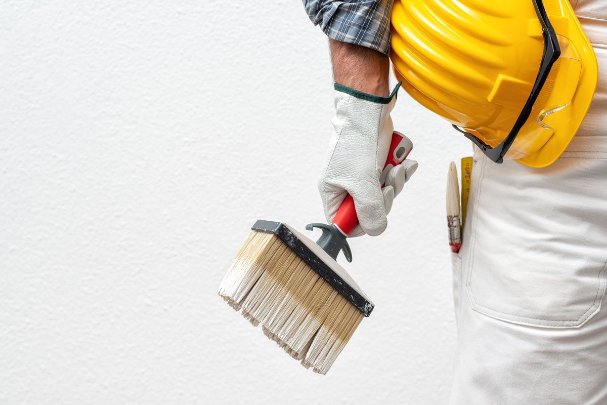 Un hombre que lleva casco y guantes sostiene un pincel.