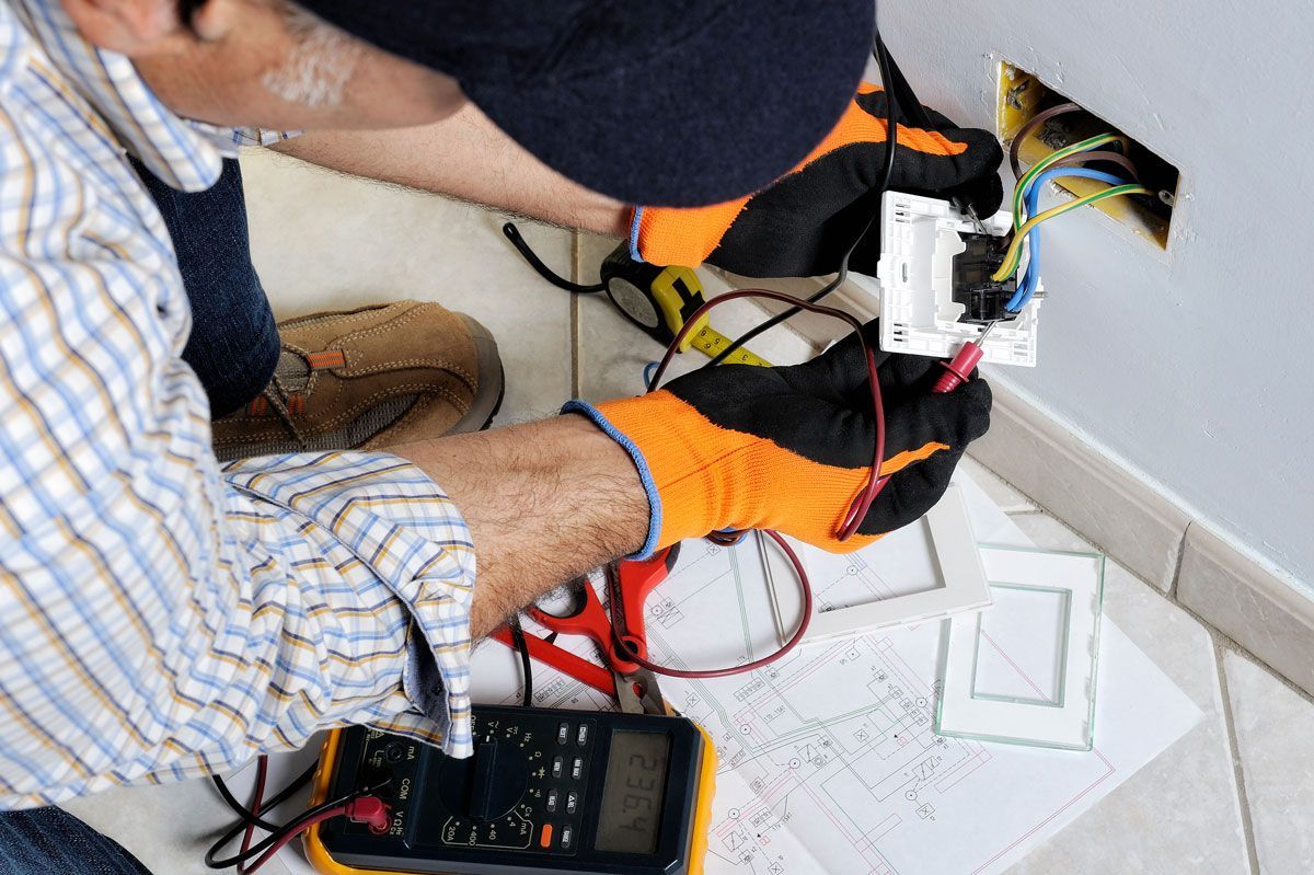 Un electricista está trabajando en un interruptor de luz con un multímetro.