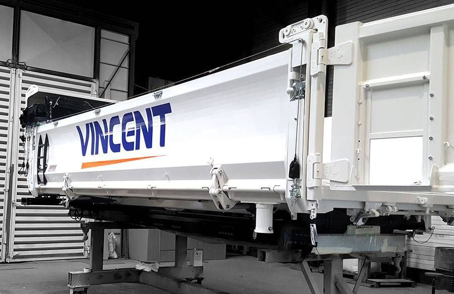 Remorque de camion-benne blanche avec le logo bleu VINCENT dans un garage d’entrepôt