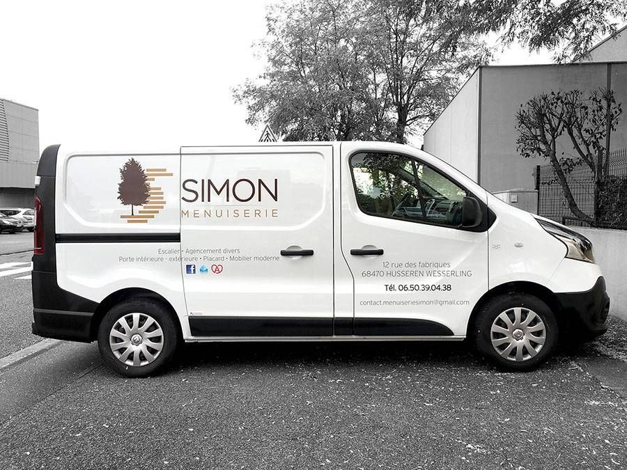 Fourgonnette de livraison blanche avec le logo Simon, garée à l’extérieur, près d’un bâtiment et d’arbres