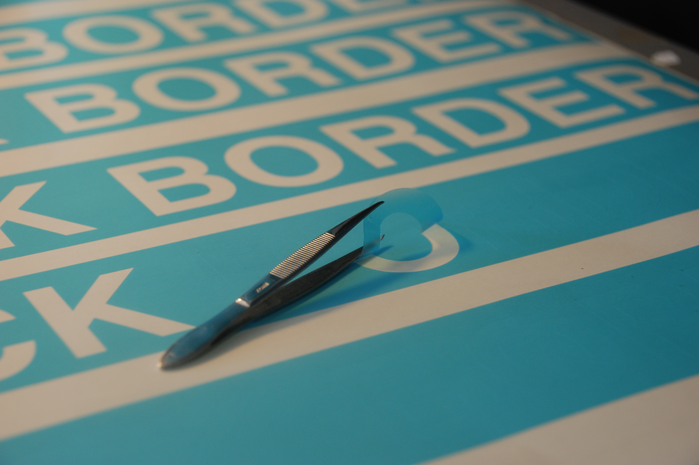 Un cutter posé sur une surface bleu canard et blanche, avec le mot « BORDER » répété