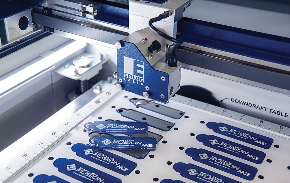 Machine de découpe laser industrielle bleue gravant des étiquettes bleues sur une feuille blanche dans un atelier de fabrication