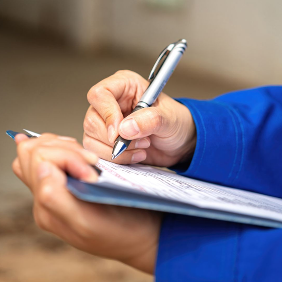 Des mains écrivant sur un bloc-notes avec un stylo argenté.