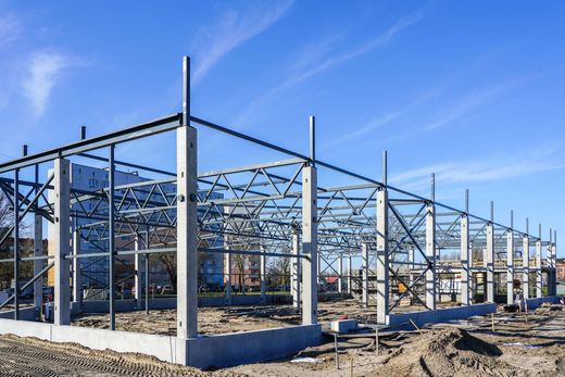 Charpente métallique d'un bâtiment en construction sur un terrain vague sous un ciel bleu