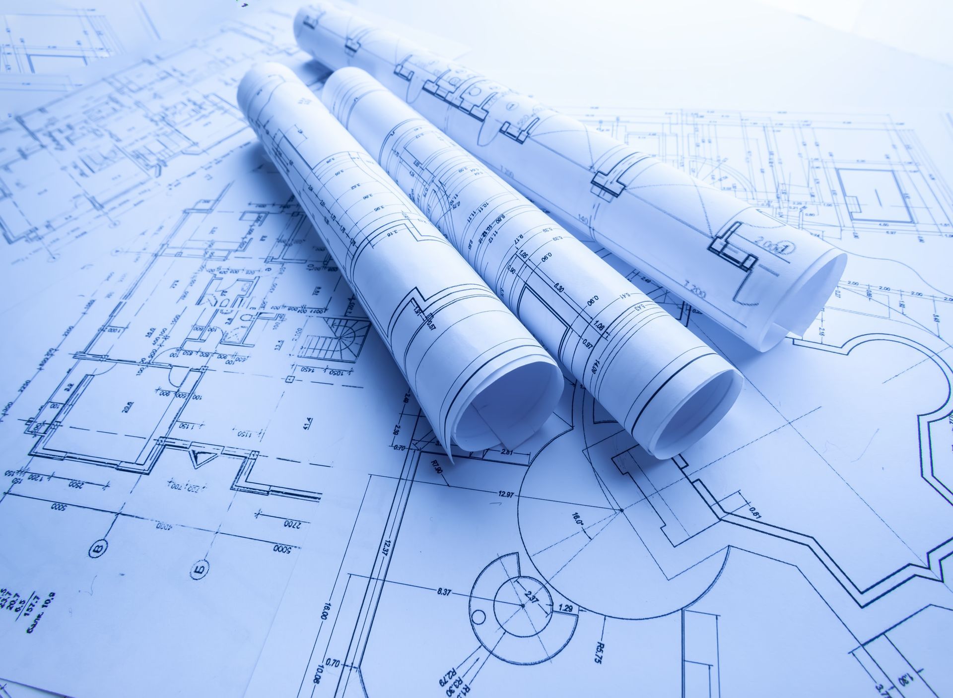 Plans d'architecte enroulés montrant des dessins techniques dan les tons bleus