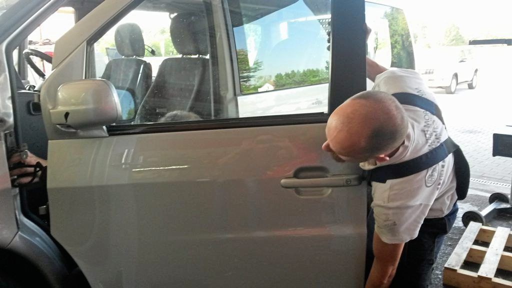 Ein Mann arbeitet in einer Garage an der Tür eines Autos.