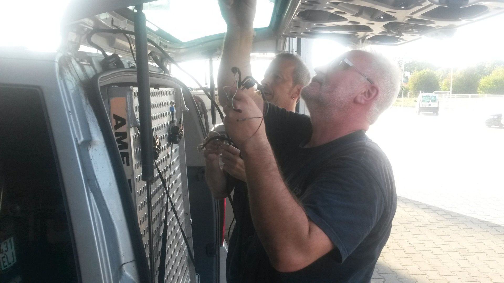 Zwei Männer arbeiten auf der Ladefläche eines Lieferwagens.