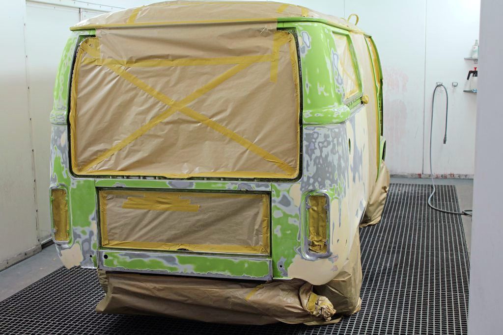 Ein grüner Lieferwagen wird in einer Lackierkabine lackiert.