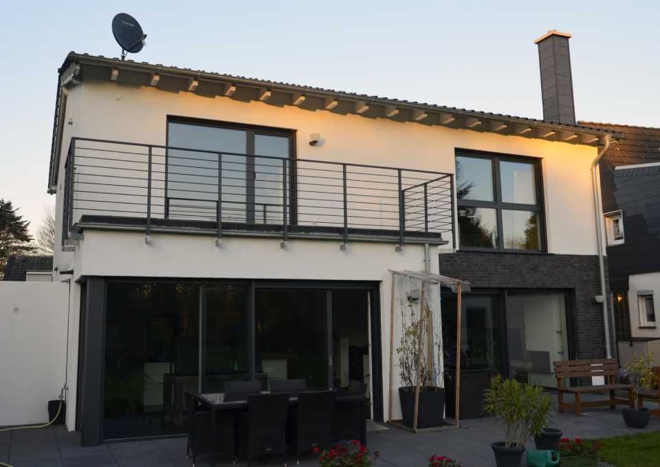 Seitenansicht eines Hauses mit großem Balkon und einer Terrasse darunter