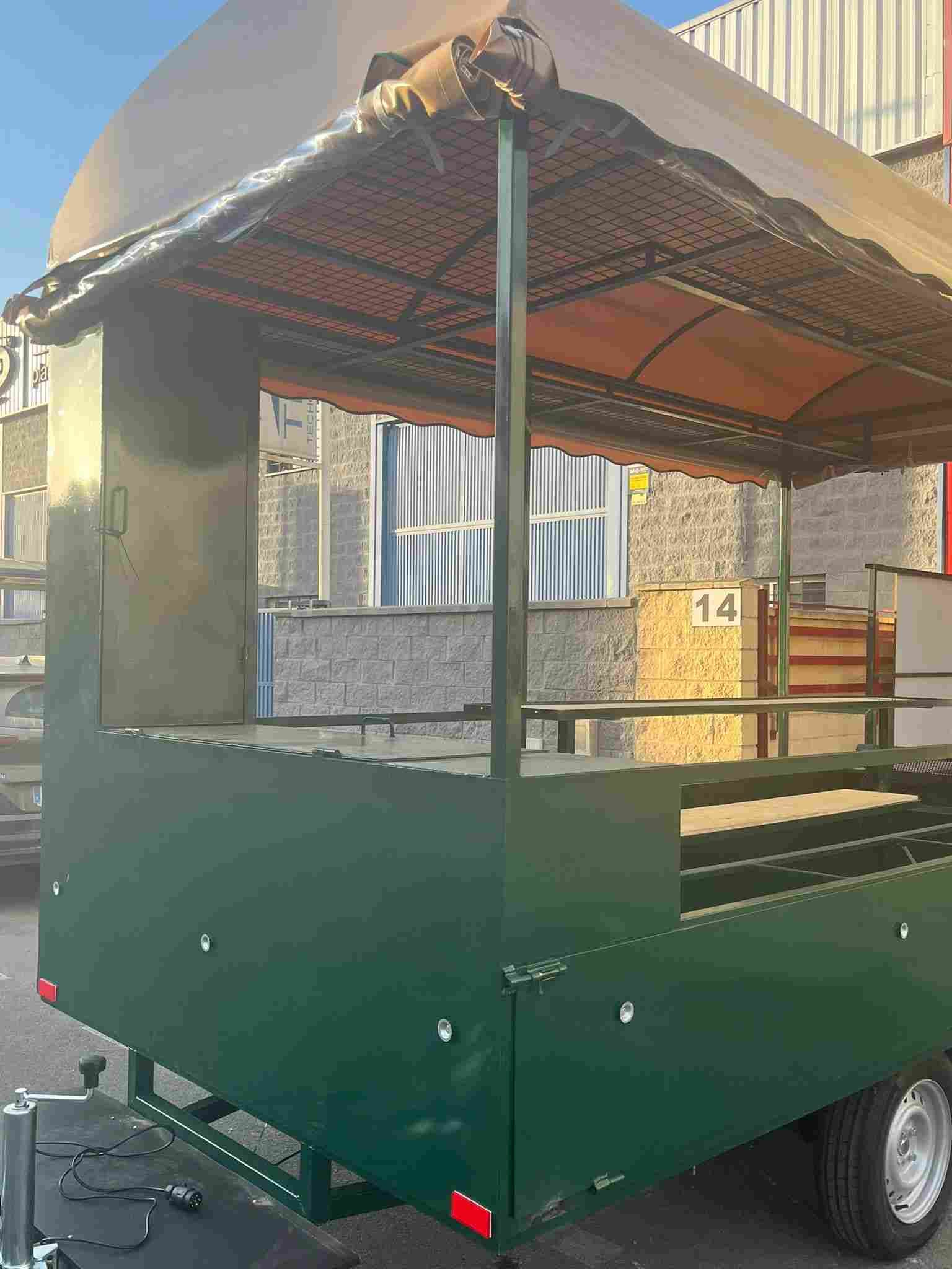 Carro de comida verde con toldo color canela, estacionado al aire libre.