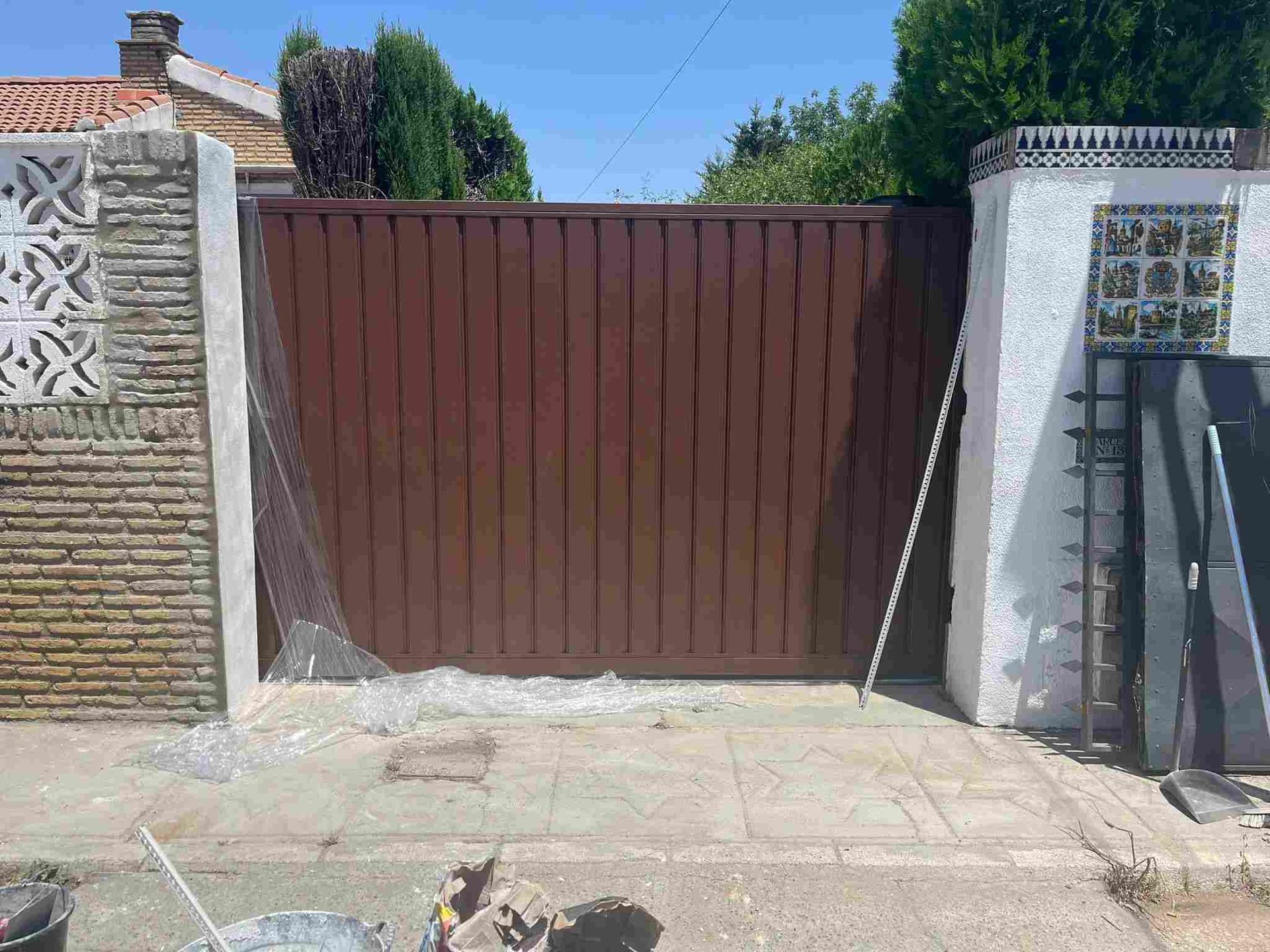 Puerta metálica de color marrón entre dos paredes de ladrillo y estuco blanco.