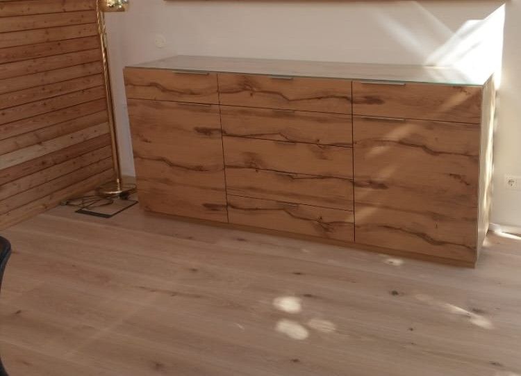 Dreitüriger Holzschrank, der auf einem hellen Holzboden steht.