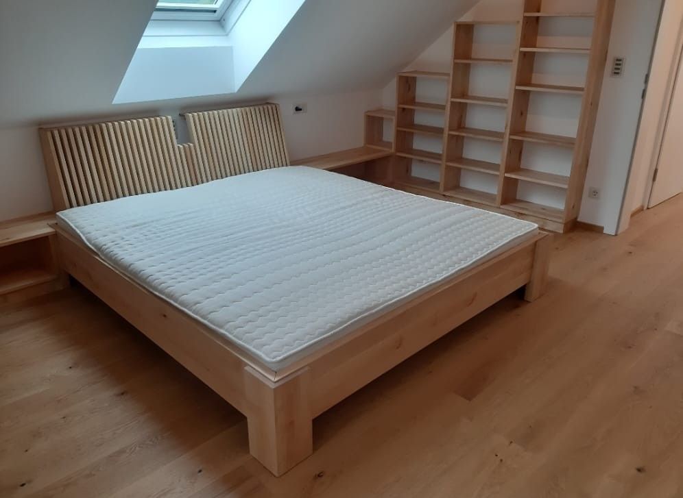 Holzbett in einem Zimmer mit eingebauten Regalen und Dachschräge.
