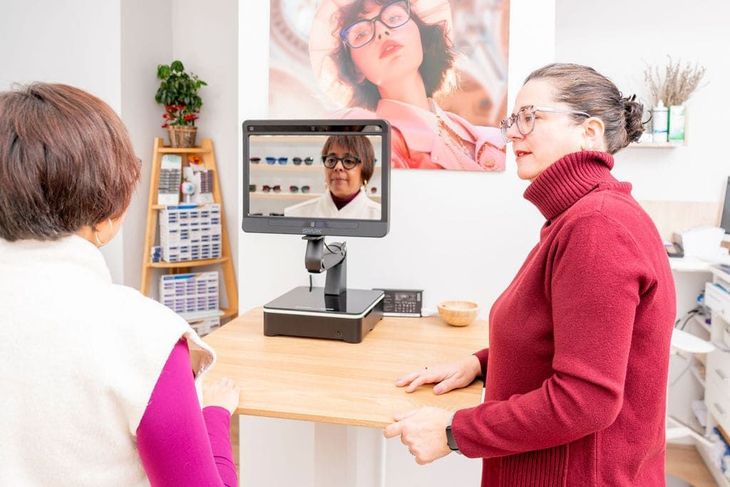 Dos mujeres en un escritorio durante una videollamada, con una tableta en un soporte en una habitación luminosa