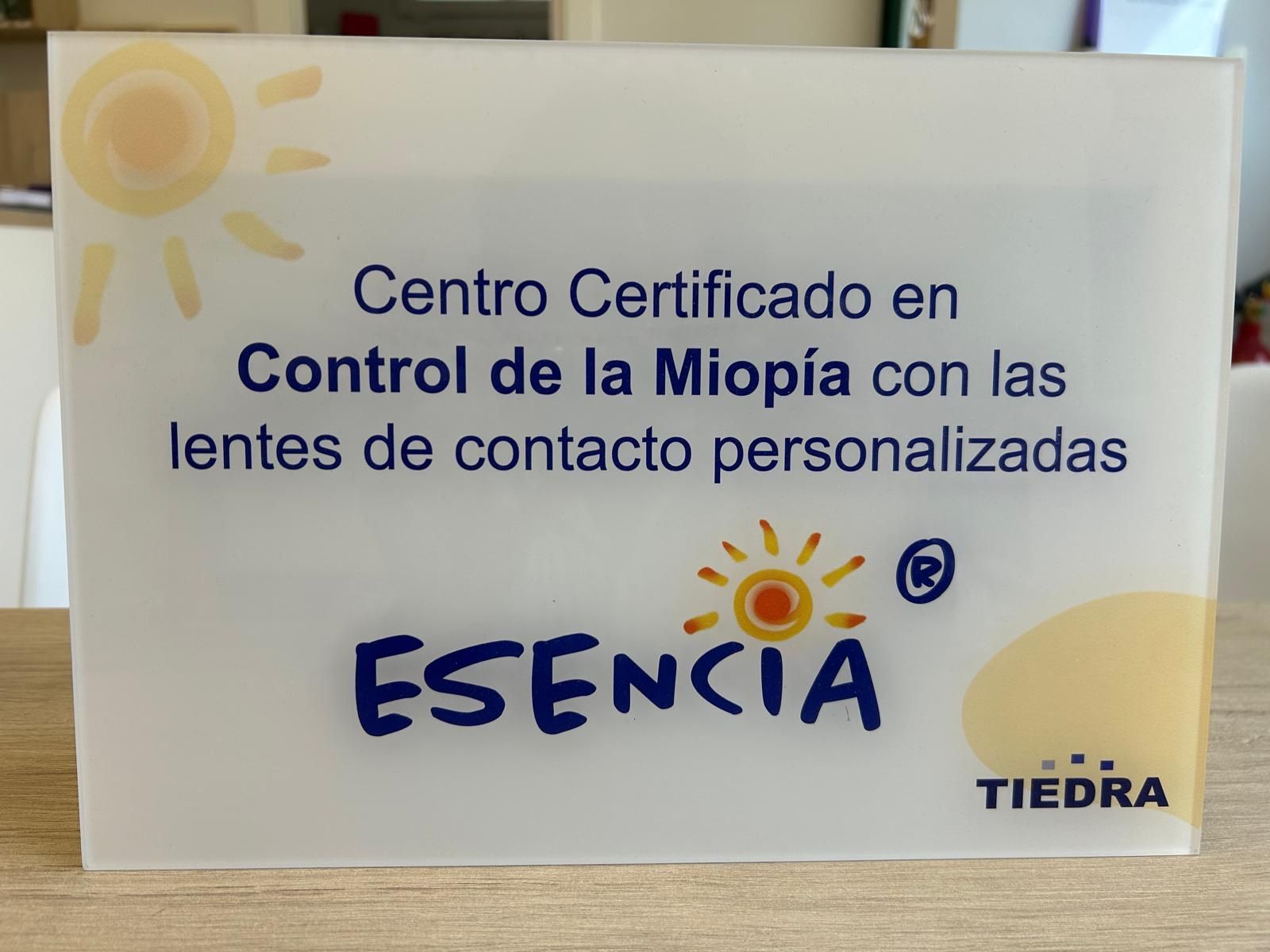 Cartel blanco de ESENCIA: centro certificado en control de la miopía con lentes de contacto personalizadas.