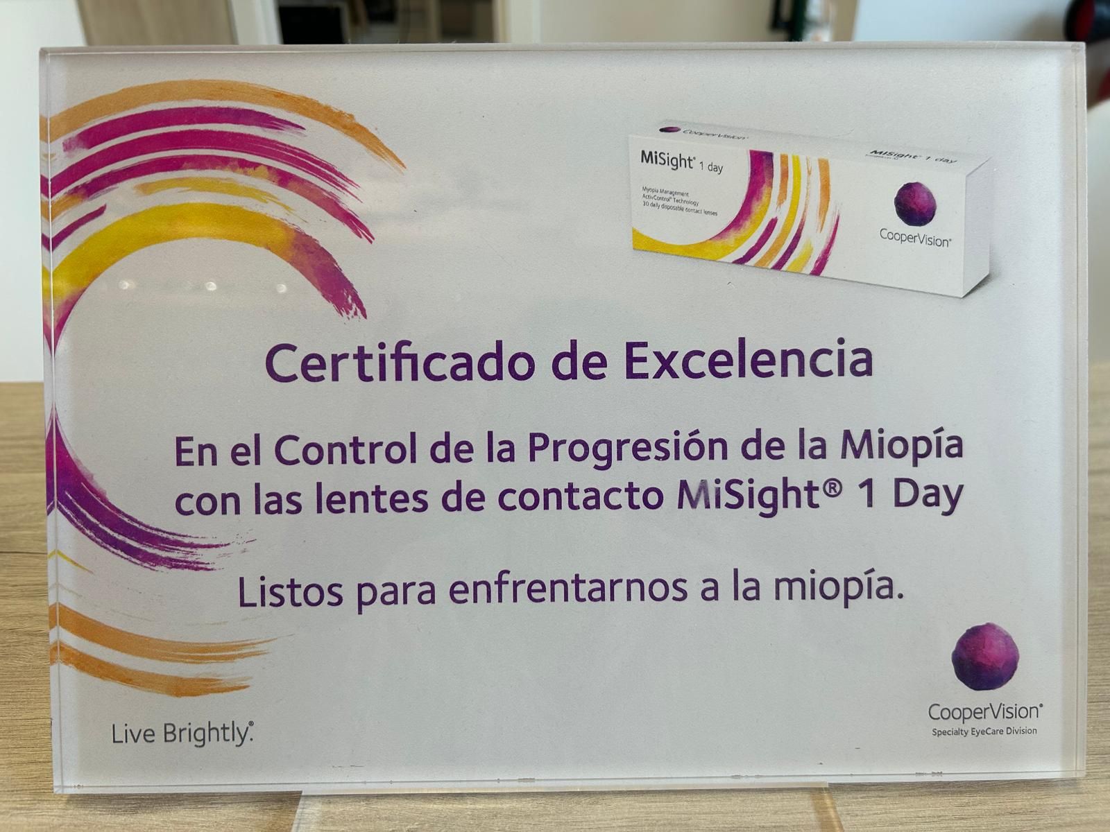 Certificado de Excelencia blanco con texto morado y logo, sobre el control de la miopía con lentes MiSight.
