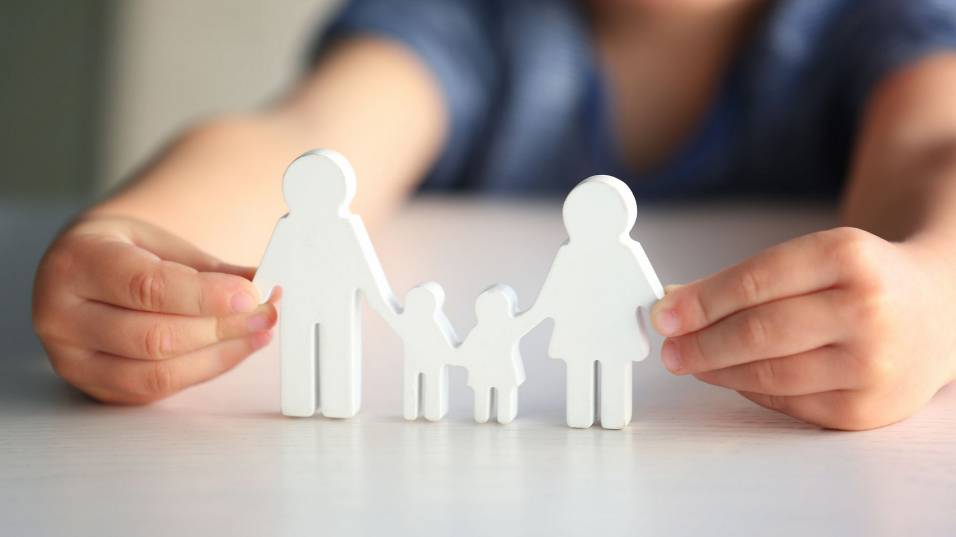 Enfant tenant une silhouette familiale blanche, représentant des parents et deux enfants.