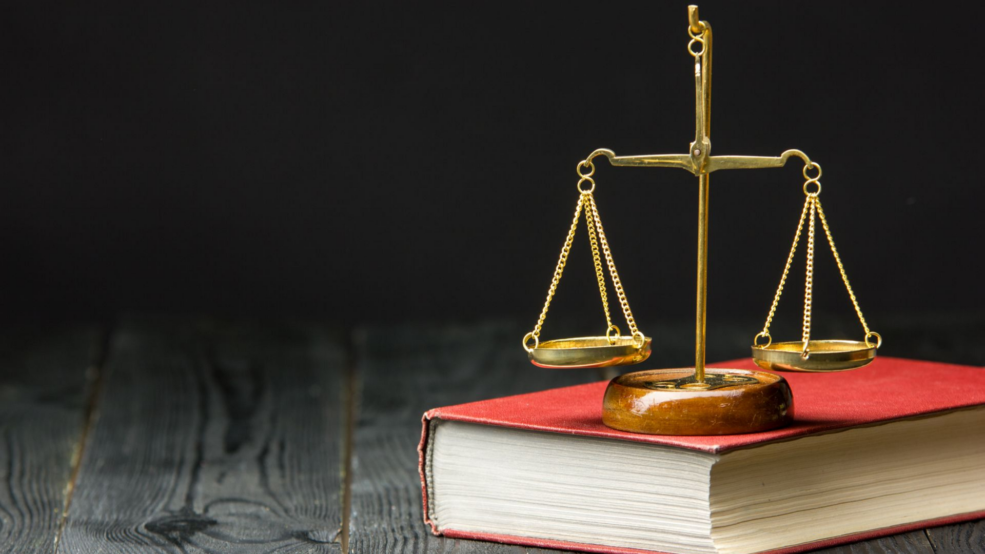 Une personne en costume est assise à un bureau avec des documents juridiques, une balance de la justice et un marteau