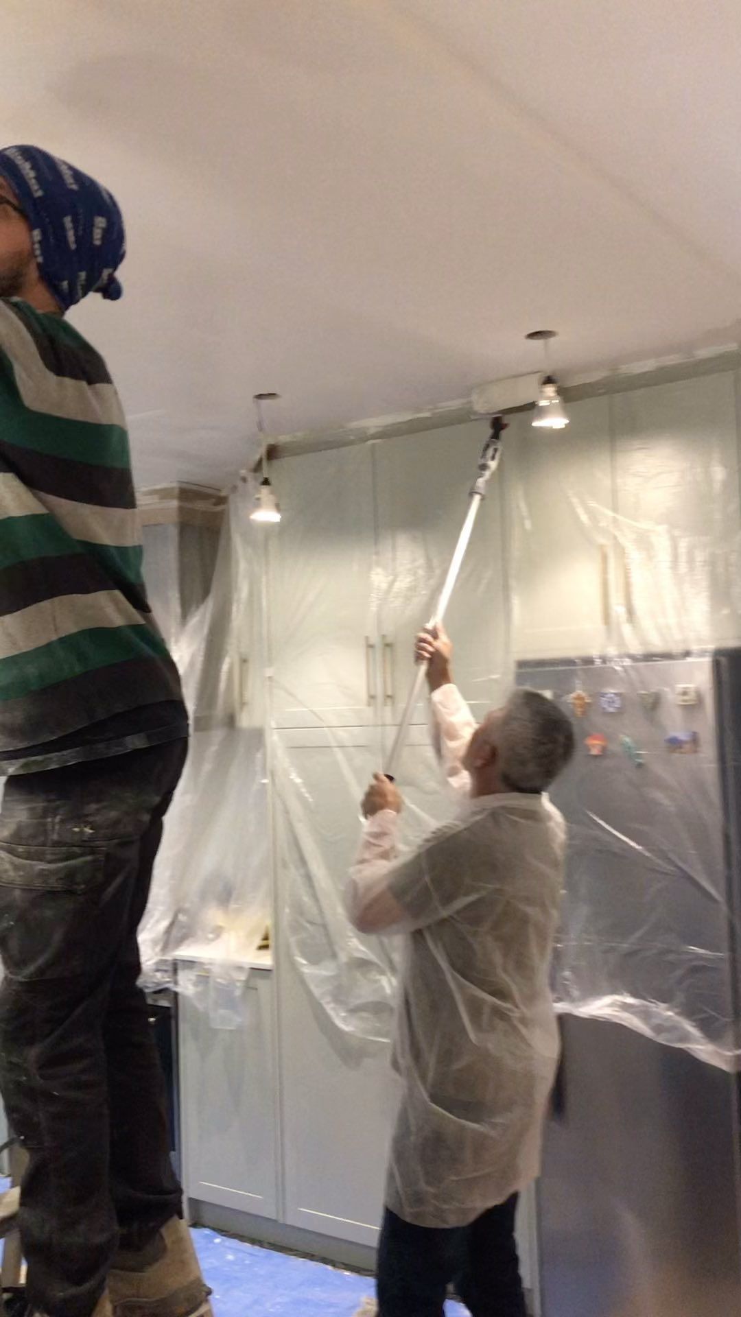 Un hombre y una mujer están pintando el techo de una habitación.