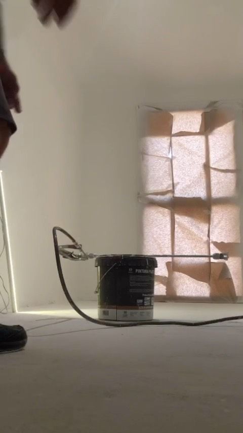 Una persona está parada en una habitación con un balde de pintura en el suelo.