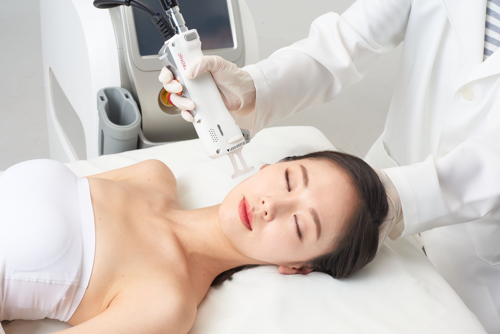 Frau erhält auf einer Spa-Liege eine Gesichtsbehandlung mit einem Handgerät