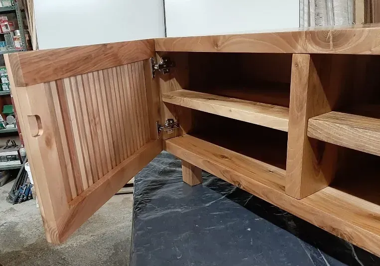 Un armario de madera con la puerta abierta está sobre una mesa.