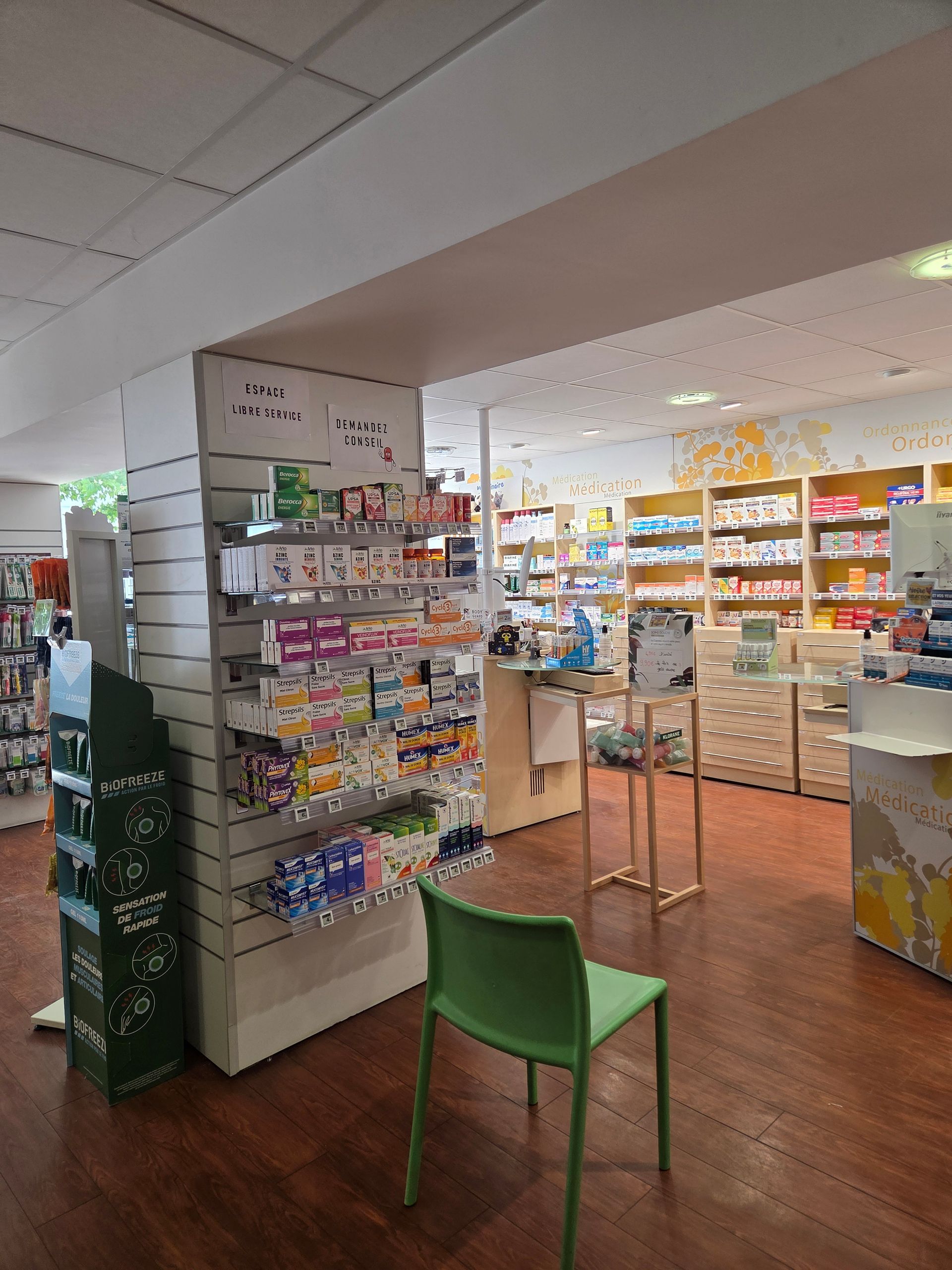 Intérieur d'une pharmacie avec des étagères remplies de produits et une chaise verte